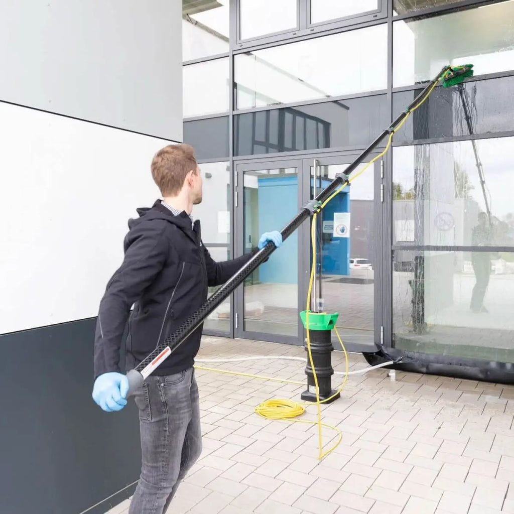 Schwarze teleskopische fensterreinigungsstange mit grünem sockel und gelbem schlauch im produkt hermes auffangwanne 3.0