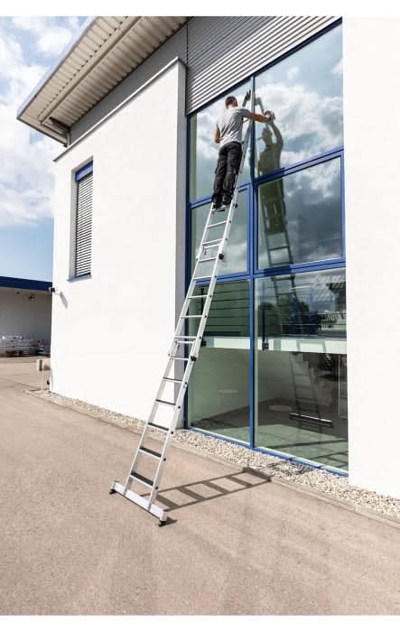 Silberne aluminium-erweiterungsleiter mit schwarzen gummifüßen und stufen im munk stufen-glasreinigerleiter oberteil mit nivello-traverse