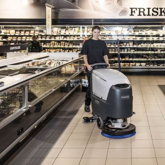 Grau schwarze nilfisk scheuersaugmaschine ba611 mit blauem bürstenkopf und ladegerät von hinten gesehen