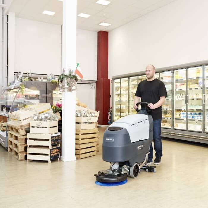 Grau weiße nilfisk scheuersaugmaschine sc401 e kabelversion mit blauem bürstenkopf im einstatz
