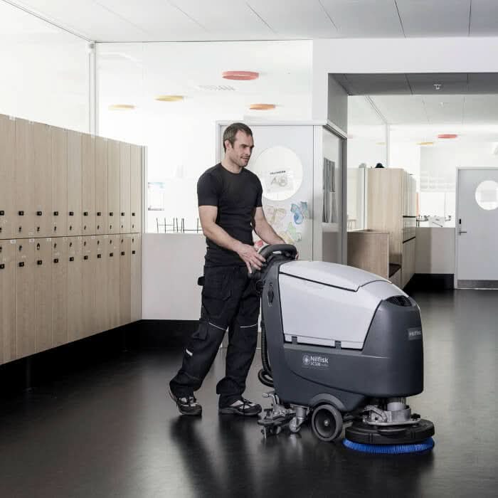 Graue und weiße nilfisk scheuersaugmaschine sc500 rev mit blauem bürstenkopf für industrielle bodenreinigung