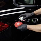 Person mit schwarzen Handschuhen sprüht Sonax Profiline Polymer NetShield 340ml auf Polierschwamm für Fahrzeugpflege