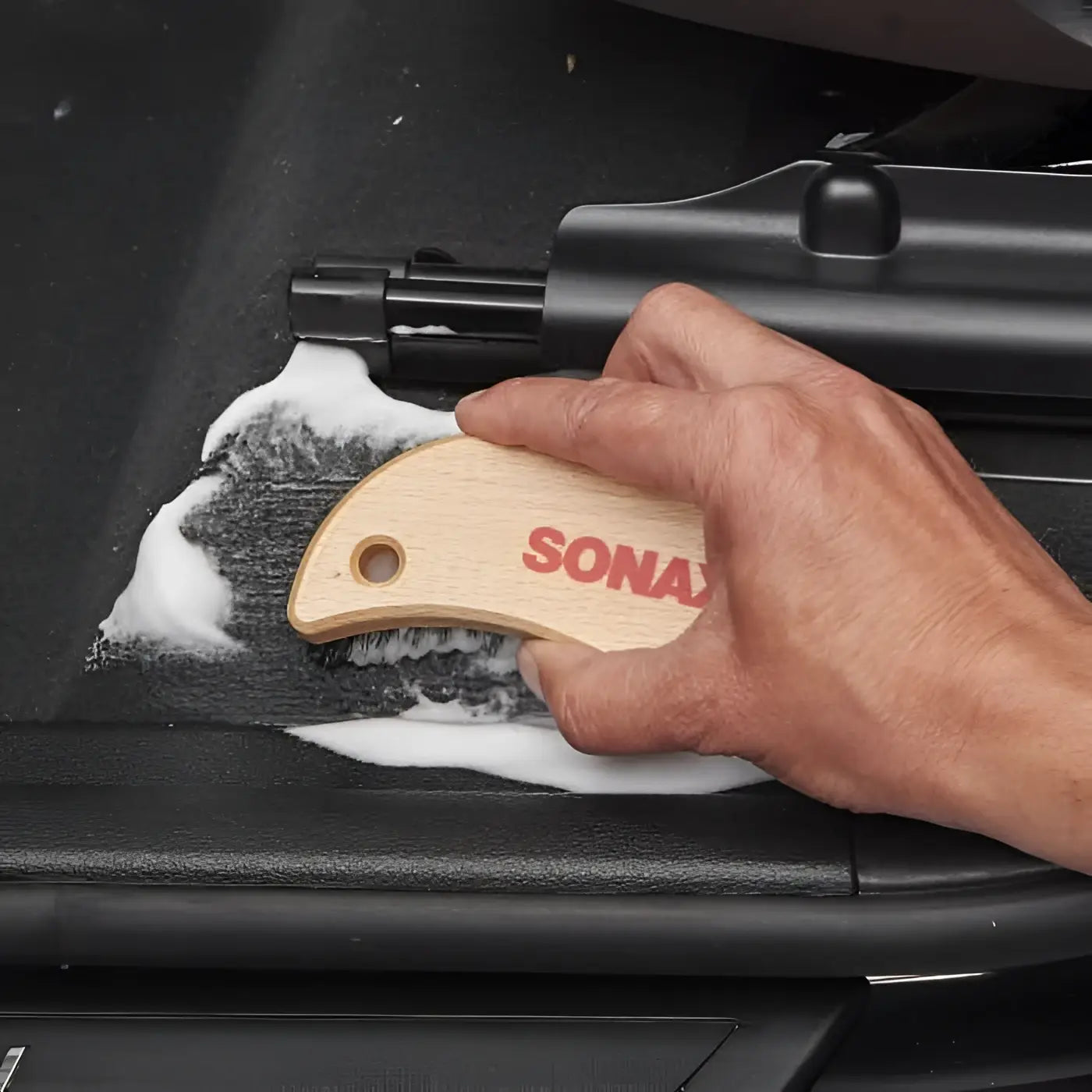 Sonax textil und lederbürste mit hellholzgriff, gebogener form und schwarzen borsten für autoreinigung