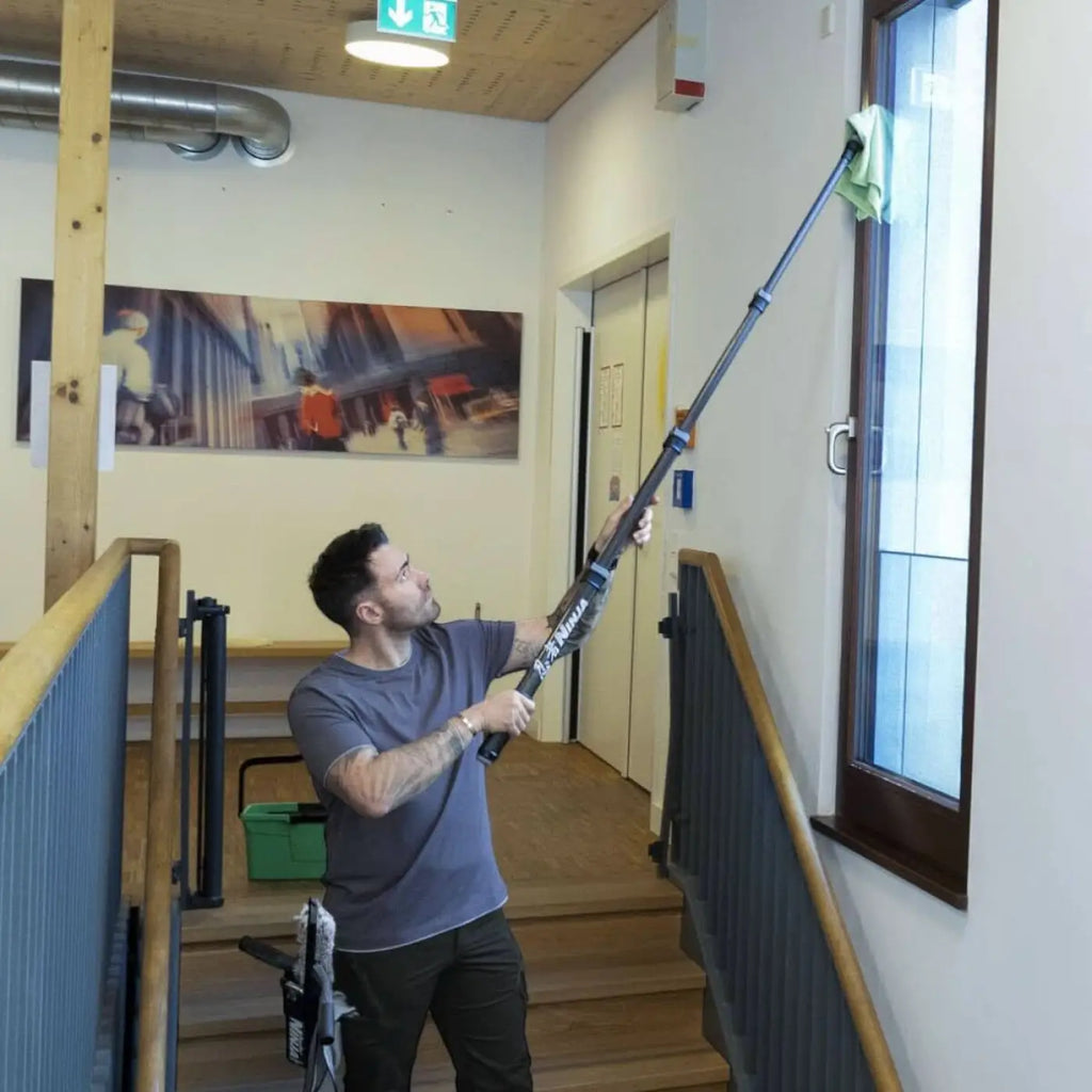 Schwarze teleskopstange aus carbon von unger ninja mit grünem mikrofaserputztuch für fensterreinigung