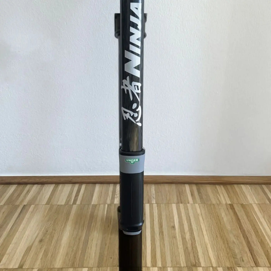 Schwarzer carbonfaser ninja scooter mit weißen japanischen zeichen und grauem griff in unger ninja 6in1 set